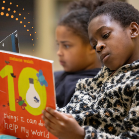 Photo of two children reading books. One is reading a book titled "10 things I can do to help my world."